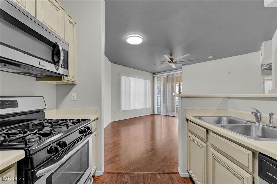 7147 South Durango Drive, Unit 304 Las Vegas, NV 89113 - Photo 9 of 27 Kitchen featuring stainless steel appliances, cream cabinetry, wood finished floors, and light countertops
