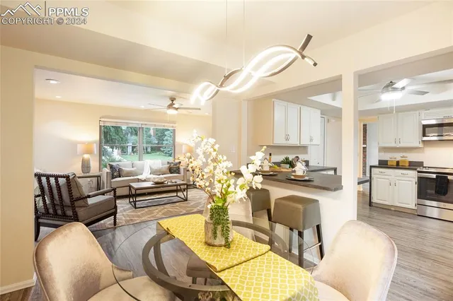 a kitchen with stainless steel appliances kitchen island granite countertop a stove a sink a dining table and chairs with wooden floor