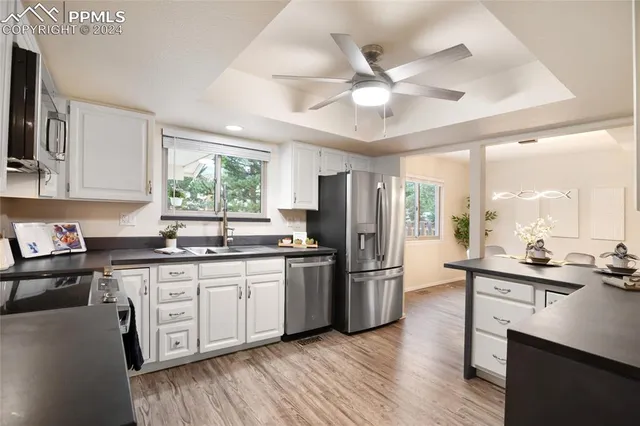 a kitchen with stainless steel appliances a sink a stove a refrigerator cabinets and wooden floor