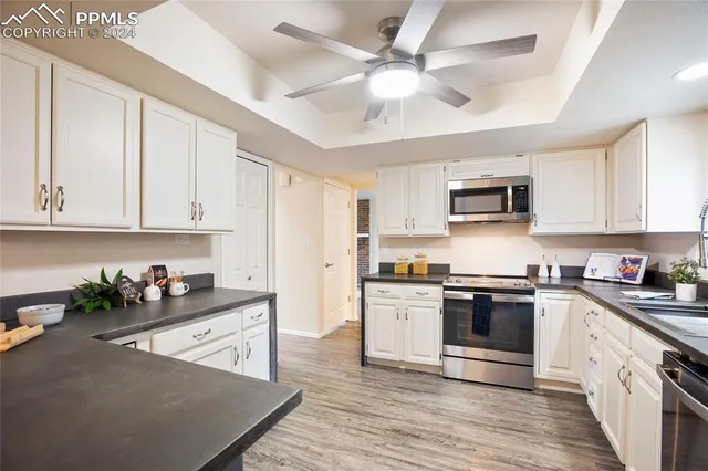 a kitchen with stainless steel appliances granite countertop white cabinets granite counter tops and a hard wood floors