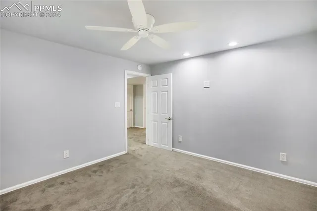 an empty room with a ceiling fan and carpet