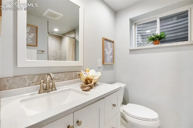 a bathroom with a granite countertop sink and a toilet