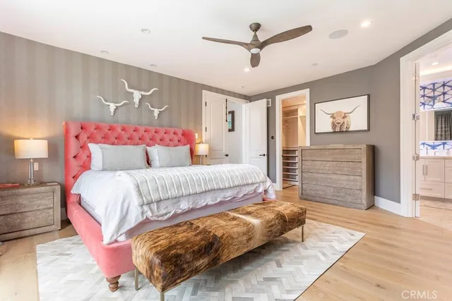 a bedroom with a bed a dresser and painting on the wall