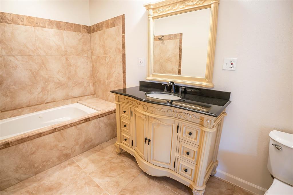 1226 Clay Street Nocona, TX 76255 - Photo 21 of 31 a spacious bathroom with a granite countertop sink a mirror and a bathtub
