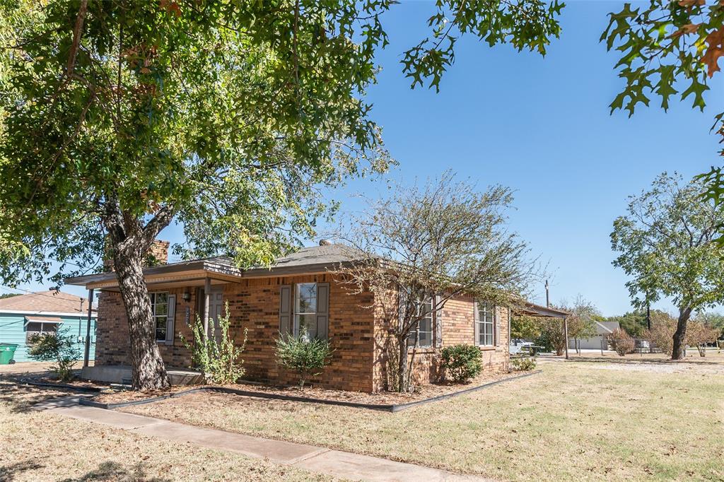 1226 Clay Street Nocona, TX 76255 - Photo 6 of 31 a front view of a house with a yard and potted plants