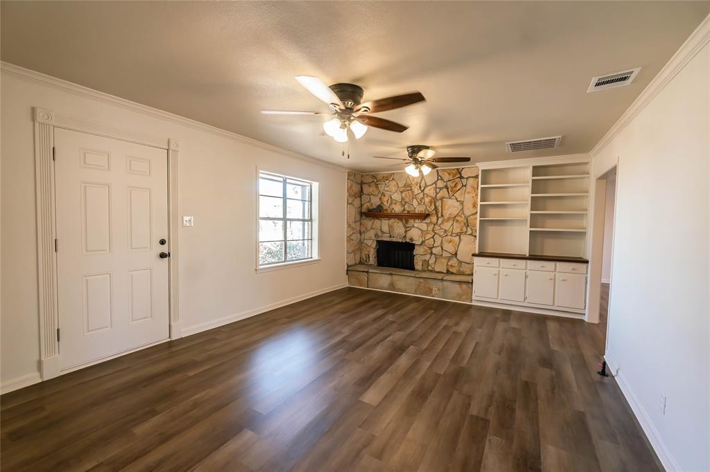 1226 Clay Street Nocona, TX 76255 - Photo 9 of 31 an empty room with wooden floor fireplace and windows