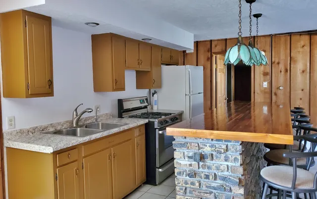 a kitchen with stainless steel appliances granite countertop a sink a stove and a wooden floor