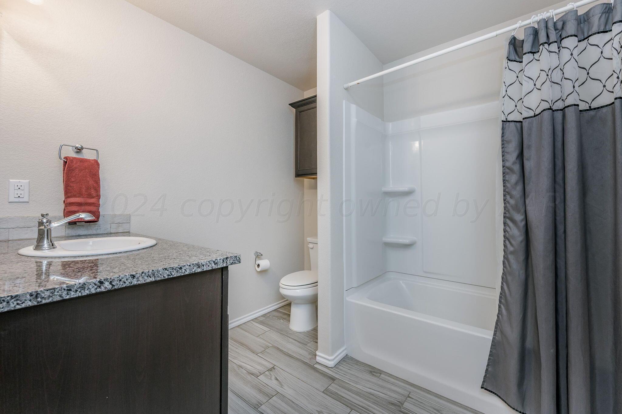 4806 Eberly Street Amarillo, TX 79118 - Photo 12 of 19 a bathroom with a granite countertop sink a toilet and shower