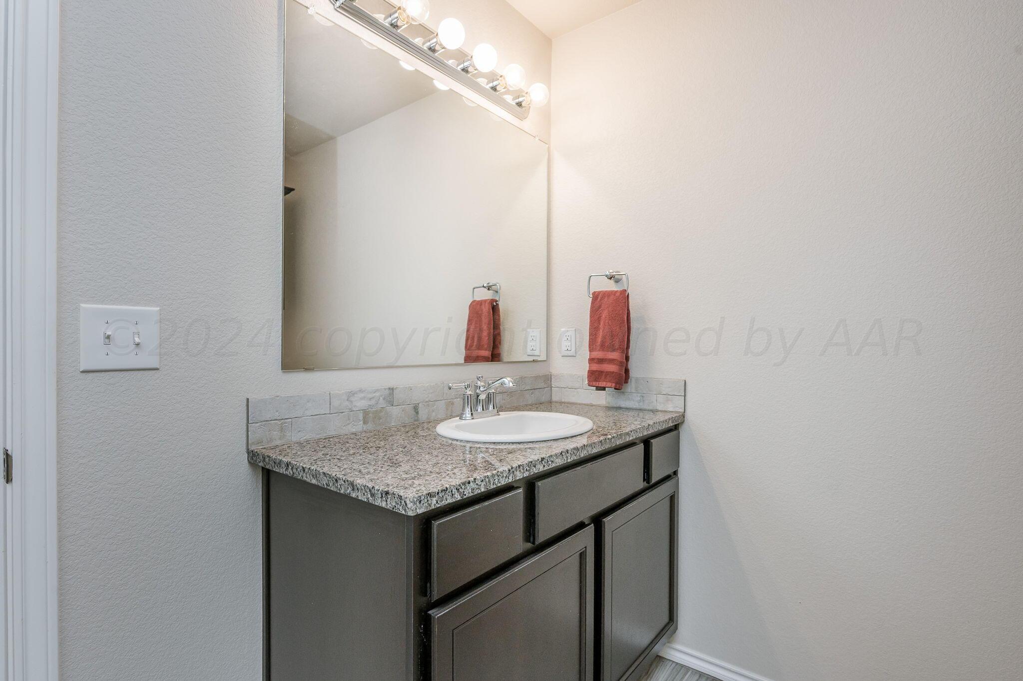 4806 Eberly Street Amarillo, TX 79118 - Photo 13 of 19 a bathroom with a granite countertop sink and a mirror