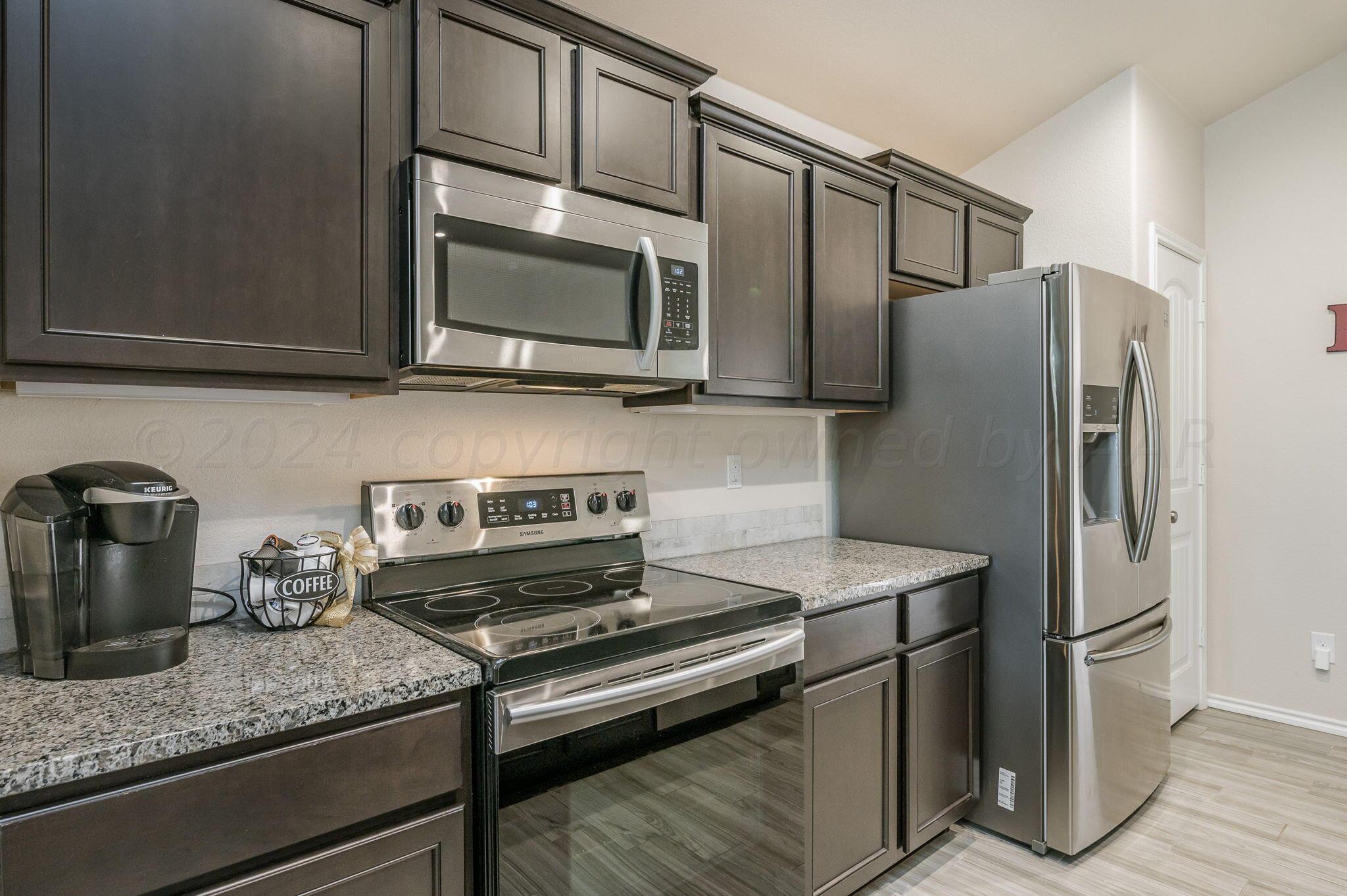 4806 Eberly Street Amarillo, TX 79118 - Photo 7 of 19 a kitchen with stainless steel appliances granite countertop a refrigerator stove and microwave