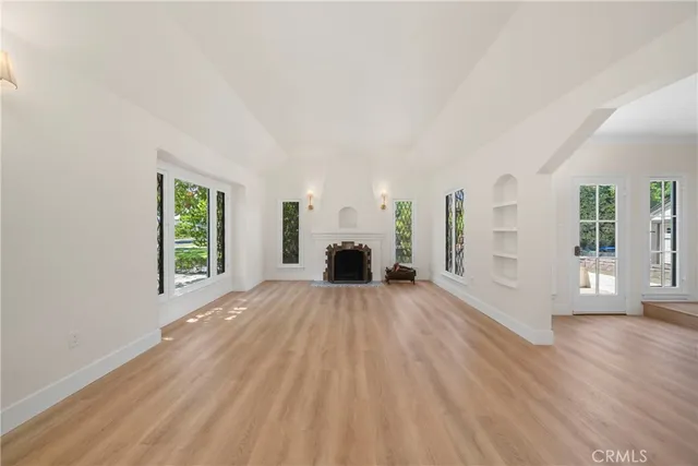 an empty room with windows and fireplace