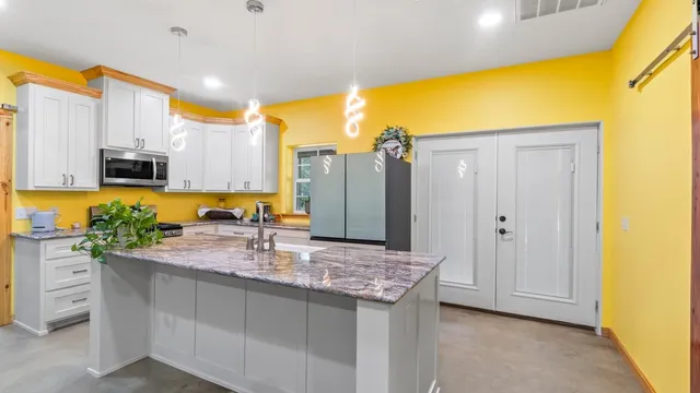 a kitchen with stainless steel appliances granite countertop a sink and a refrigerator