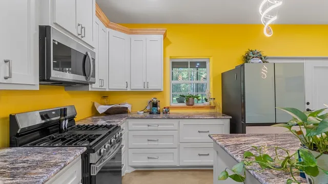 a kitchen with stainless steel appliances granite countertop a stove a sink and a microwave