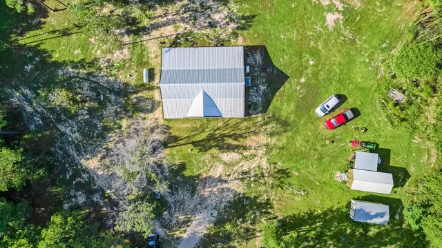 an aerial view of residential house with outdoor space and trees all around