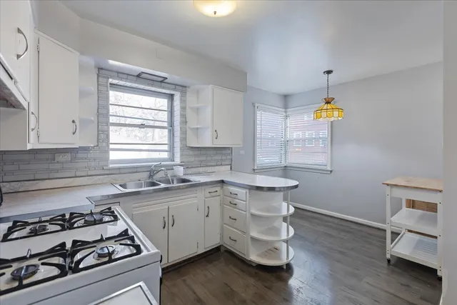 a kitchen with a stove white cabinets sink and dishwasher