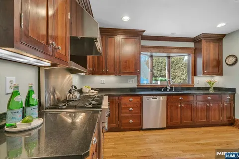 a kitchen with stainless steel appliances wooden cabinets granite counter tops and a window