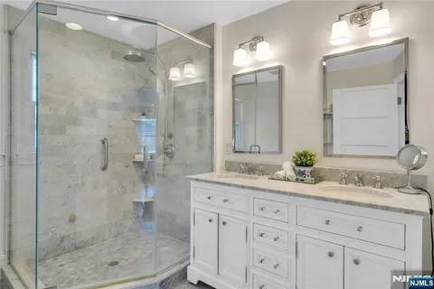 a bathroom with a granite countertop sink a mirror and a shower
