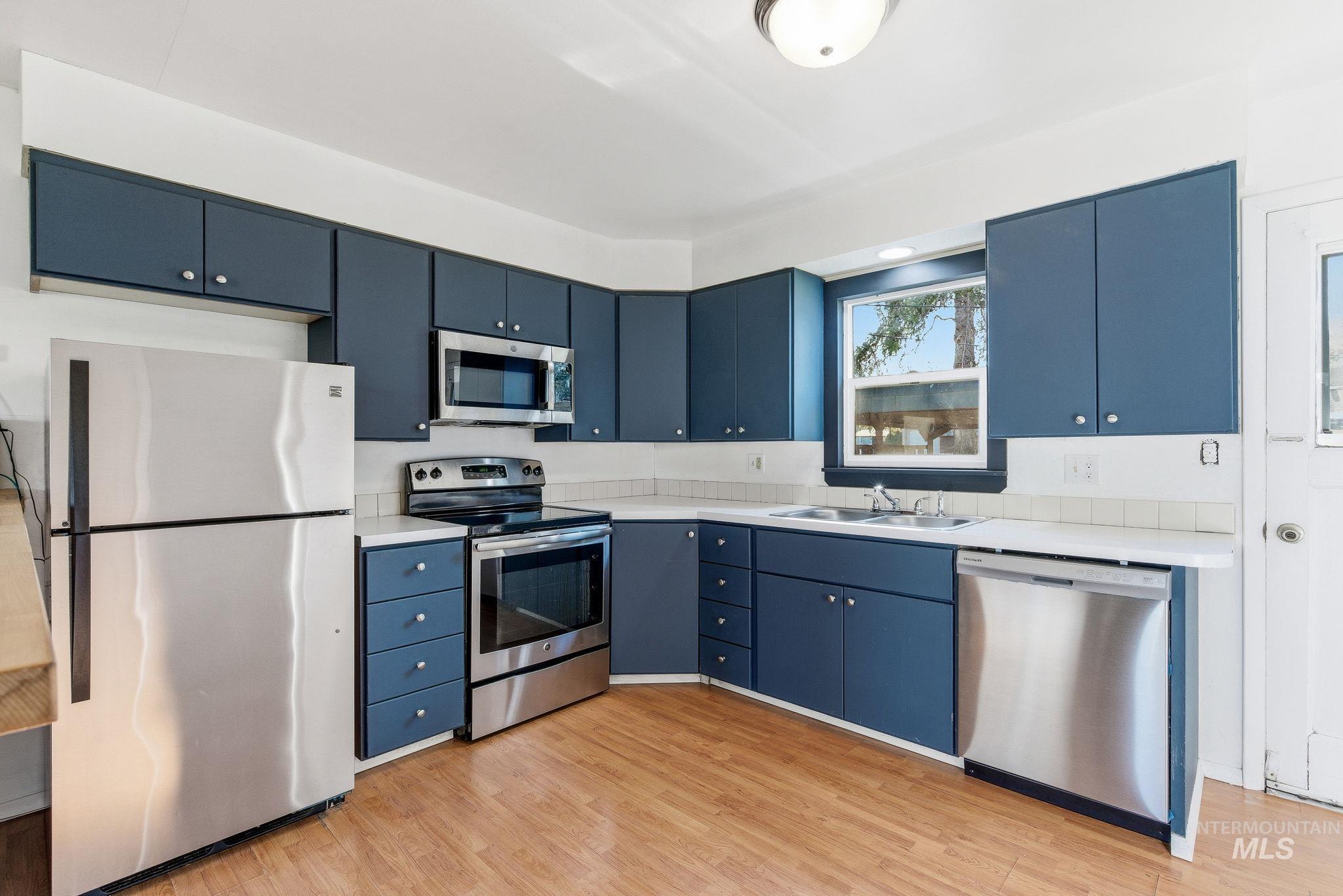 5603 West Edson Street Boise, ID 83705 - Photo 17 of 43 Kitchen featuring blue cabinets, appliances with stainless steel finishes, light countertops, and light wood finished floors