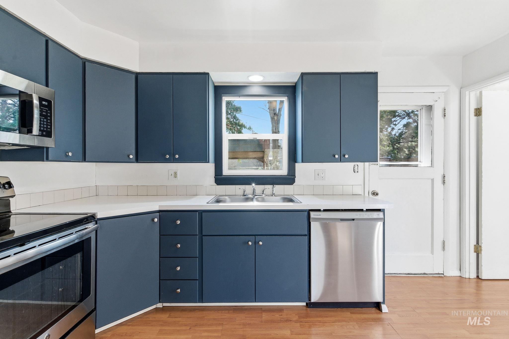 5603 West Edson Street Boise, ID 83705 - Photo 18 of 43 Kitchen with appliances with stainless steel finishes, blue cabinetry, light countertops, and light wood finished floors
