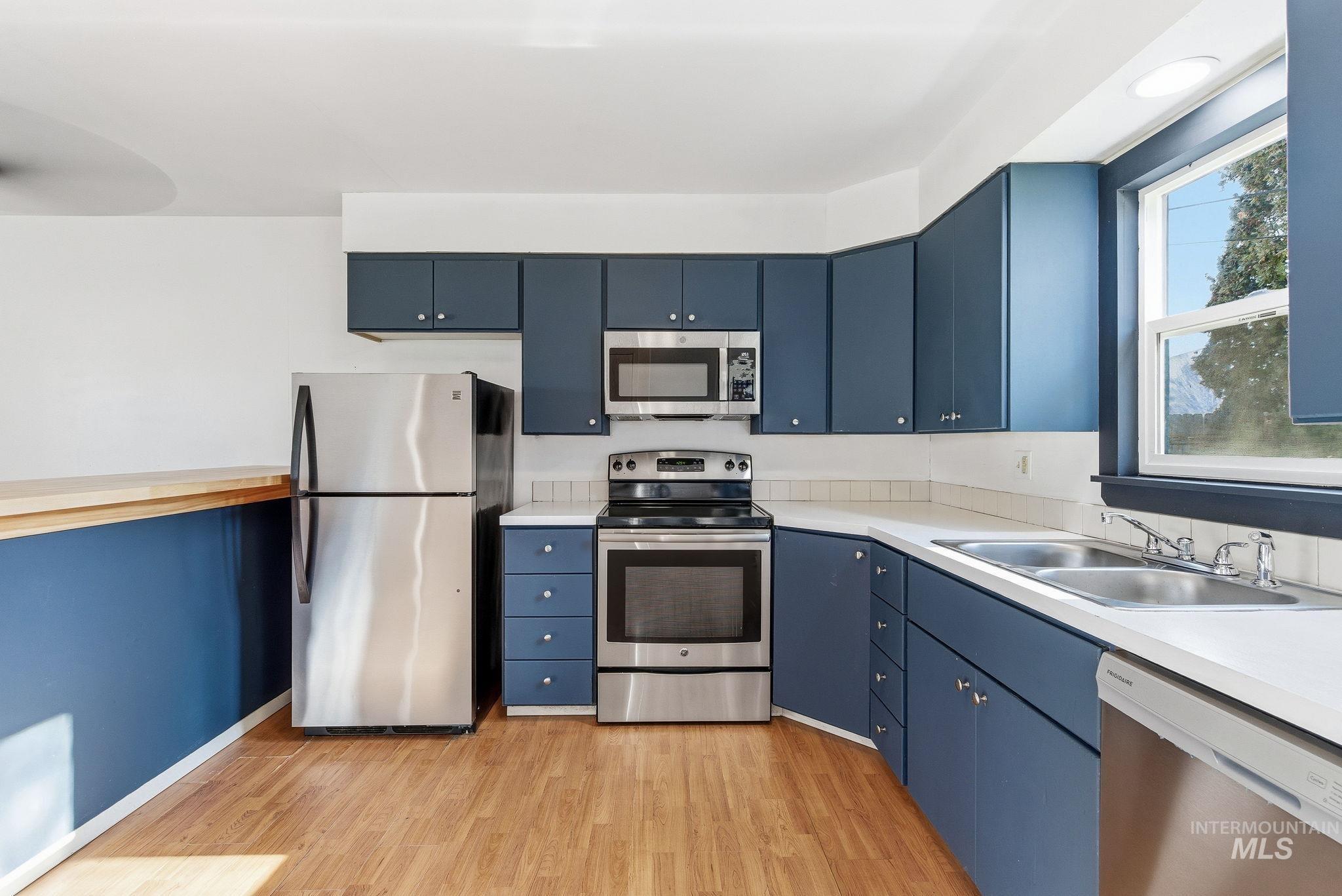 5603 West Edson Street Boise, ID 83705 - Photo 19 of 43 Kitchen featuring blue cabinets, appliances with stainless steel finishes, light countertops, and light wood-type flooring