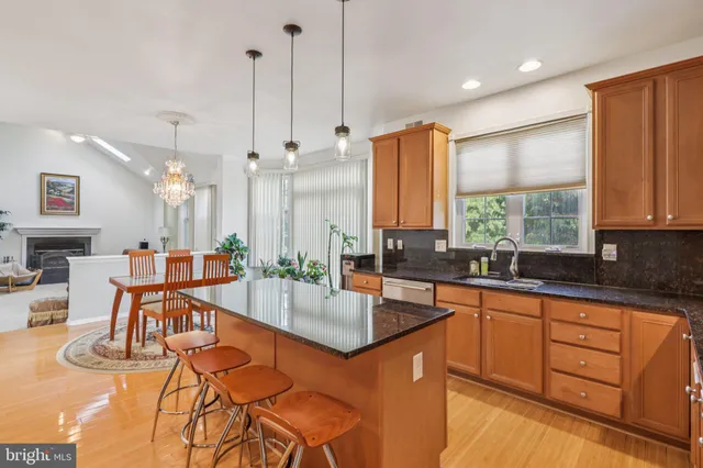a kitchen with stainless steel appliances granite countertop a sink a stove and a wooden floors