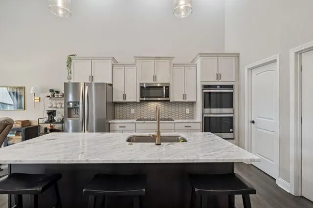 a kitchen with stainless steel appliances a dining table chairs microwave and refrigerator