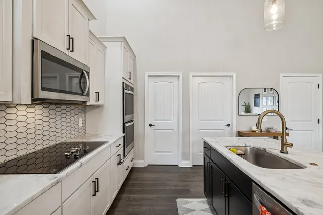 a kitchen with stainless steel appliances granite countertop a sink stove top oven and wooden floor