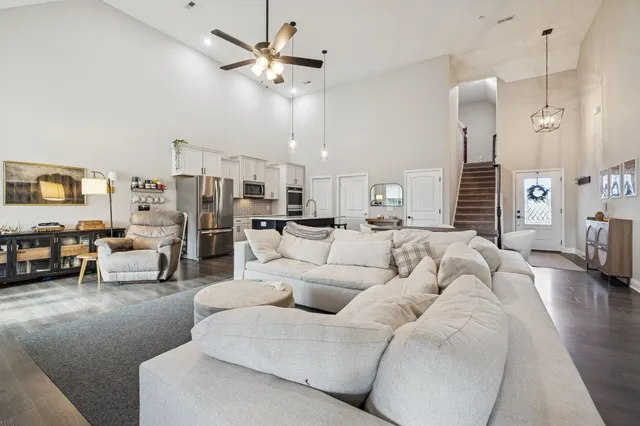 a living room with furniture kitchen view and a chandelier