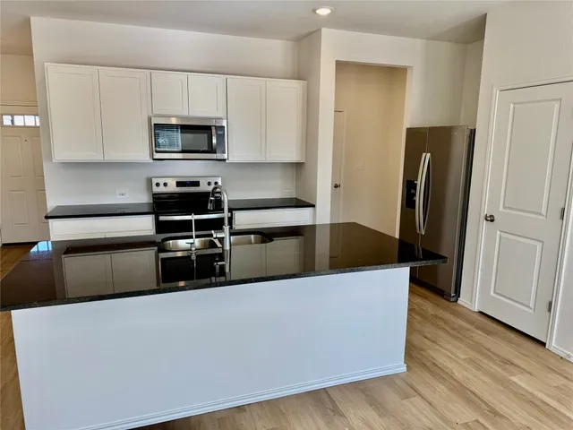 a kitchen with stainless steel appliances a refrigerator a stove a microwave and cabinets