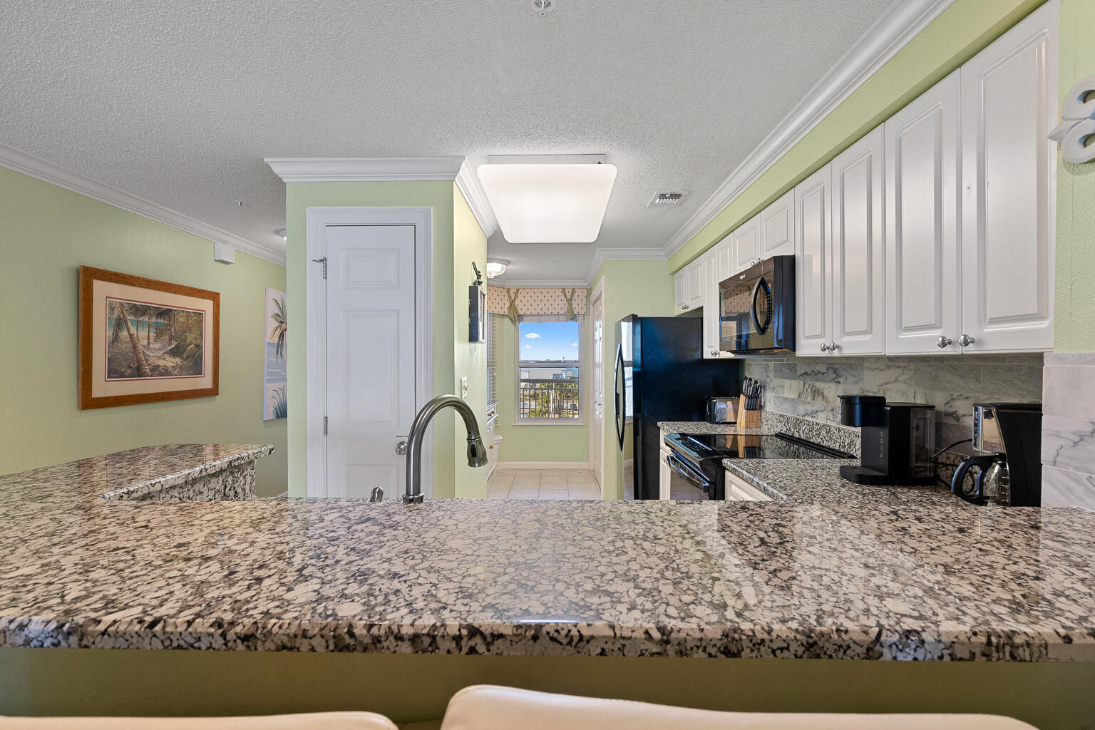8499 Gulf Boulevard, Unit 303 Navarre, FL 32566 - Photo 34 of 52 a kitchen with stainless steel appliances granite countertop a stove a sink and a microwave