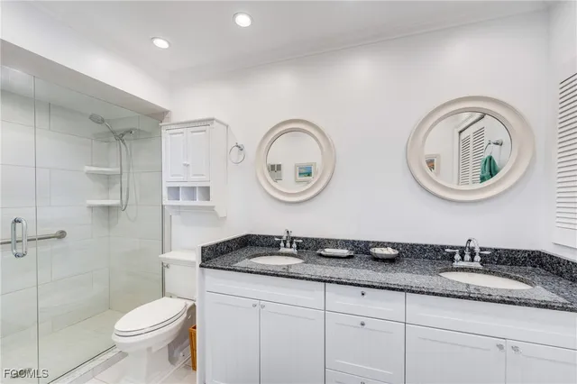 a bathroom with a granite countertop double vanity sinks and a toilet