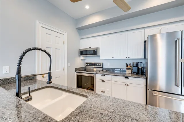 a kitchen with stainless steel appliances granite countertop a stove top oven a sink refrigerator and cabinets