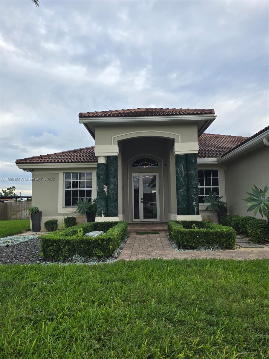12944 Southwest 222nd Street Miami, FL 33170 - Photo 3 of 44 a view of a house with brick walls and a yard