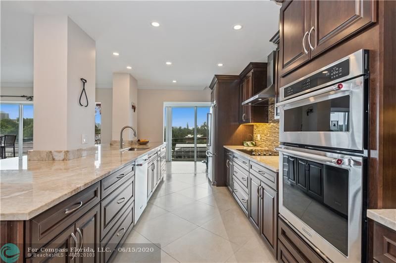 3050 Northeast 47th Court, Unit 301 Fort Lauderdale, FL 33308 - Photo 4 of 19 a kitchen with stainless steel appliances granite countertop a kitchen island wooden cabinets and granite counter tops