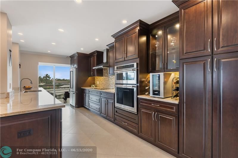 3050 Northeast 47th Court, Unit 301 Fort Lauderdale, FL 33308 - Photo 6 of 19 a kitchen with stainless steel appliances granite countertop a refrigerator and wooden cabinets