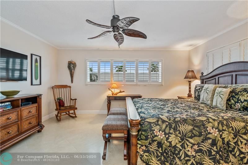 3050 Northeast 47th Court, Unit 301 Fort Lauderdale, FL 33308 - Photo 9 of 19 a bedroom with a bed and a chandelier