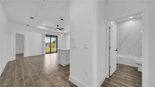 a view of a hallway with wooden floor and a bathroom