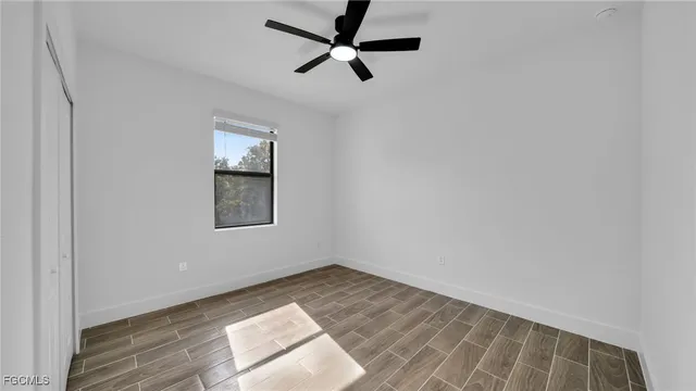 an empty room with a window and a fan