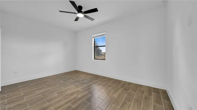 an empty room with a window and a ceiling fan