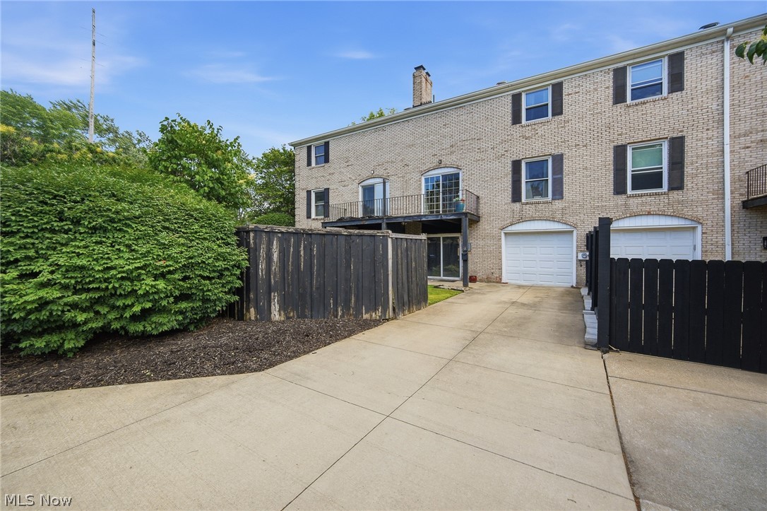 824 South Chillicothe Road, Unit 2 Aurora, OH 44202 - Photo 36 of 42 Brick exterior with multiple levels, featuring individual garage bays with white doors, black louvered shutters, and a private balcony with metal railings