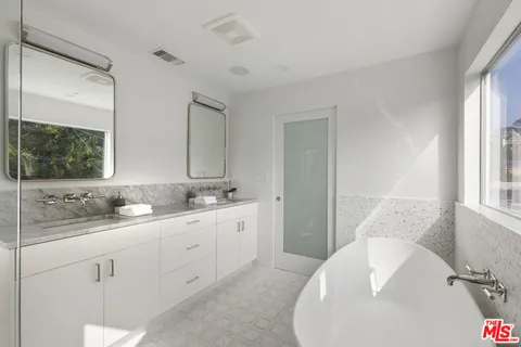 a en suite bathroom with a double vanity sink a mirror and a bathtub