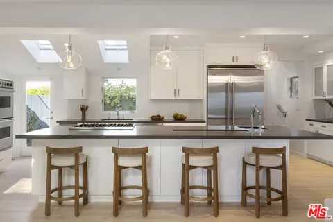 a kitchen with white cabinets and chairs