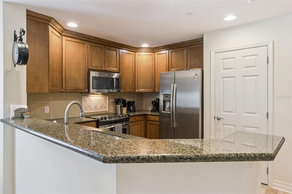 7650 Whisper Way, Unit 204 Reunion, FL 34747 - Photo 13 of 29 a kitchen with stainless steel appliances granite countertop a refrigerator a stove a sink a microwave and island