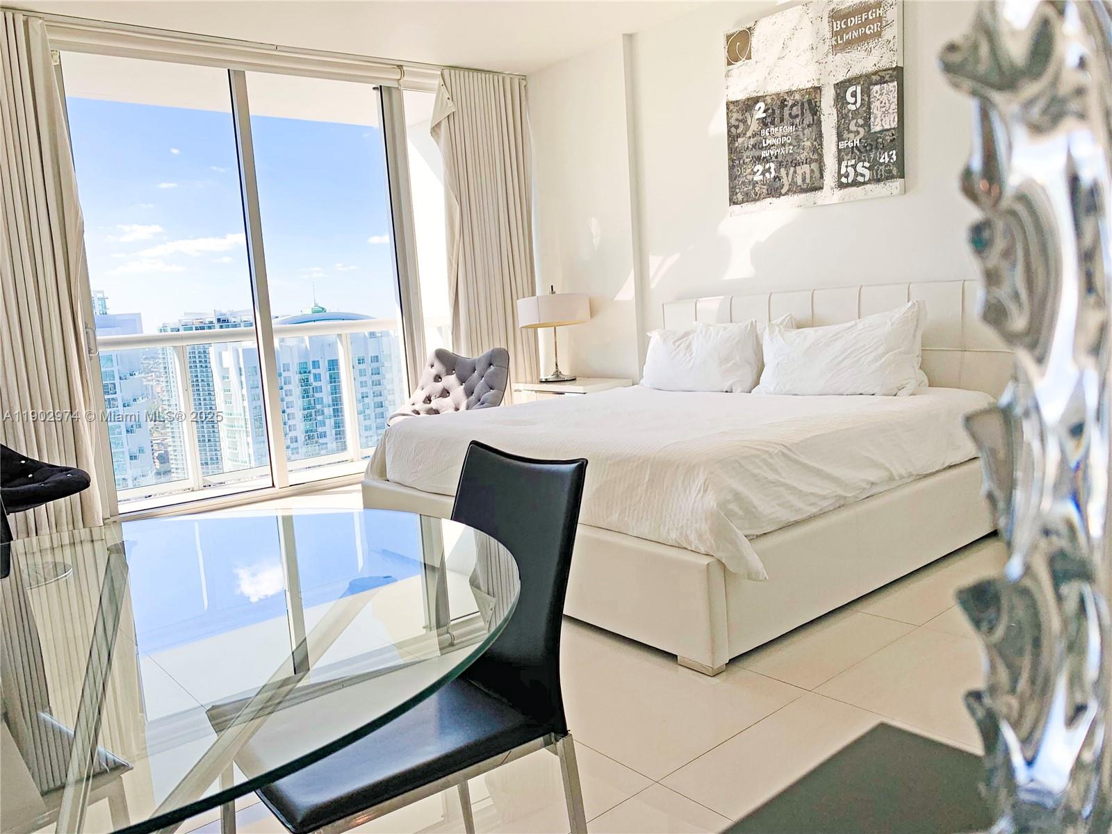 Icon Brickell Miami, FL 33131 - Photo 5 of 13 a bedroom with a bed and a large window with outer view