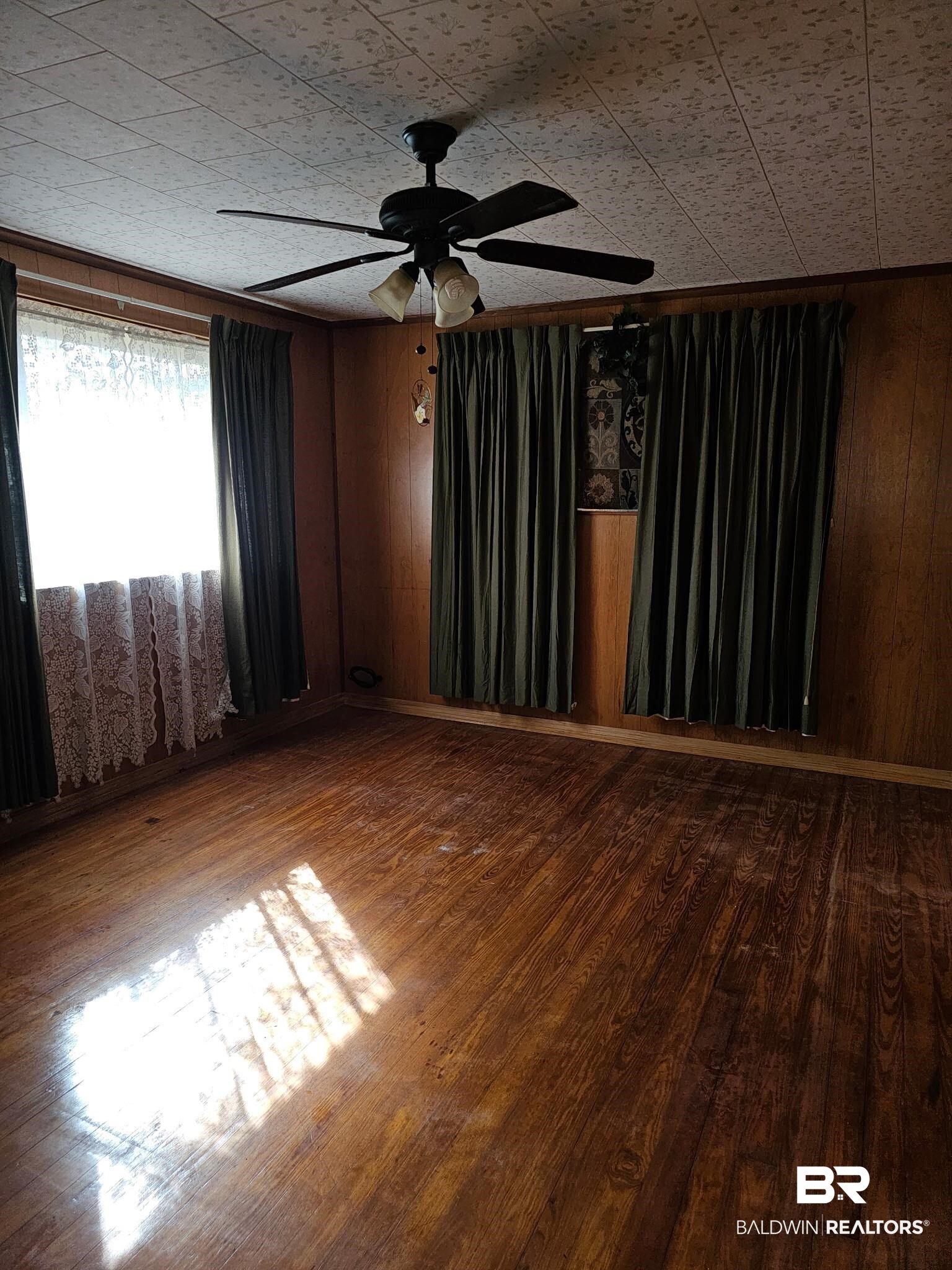304 Sutherland Drive Mobile, AL 36611 - Photo 11 of 18 Empty room featuring wood-type flooring, ceiling fan, and wood walls