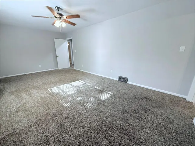 a view of an empty room with a chandelier fan
