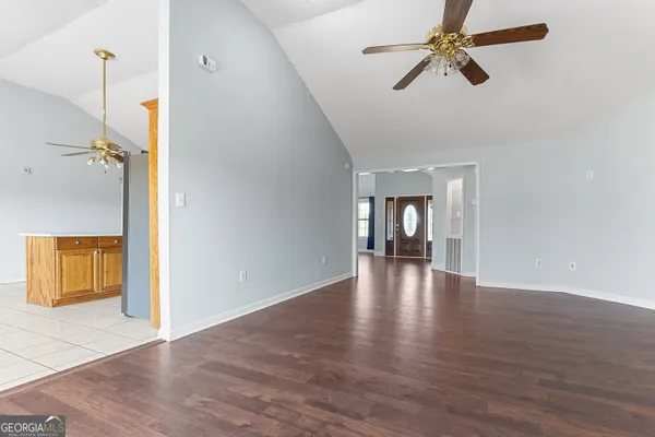 a view of empty room with wooden floor and ceiling fan