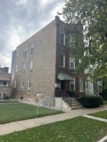 a view of a brick building next to a yard with big trees