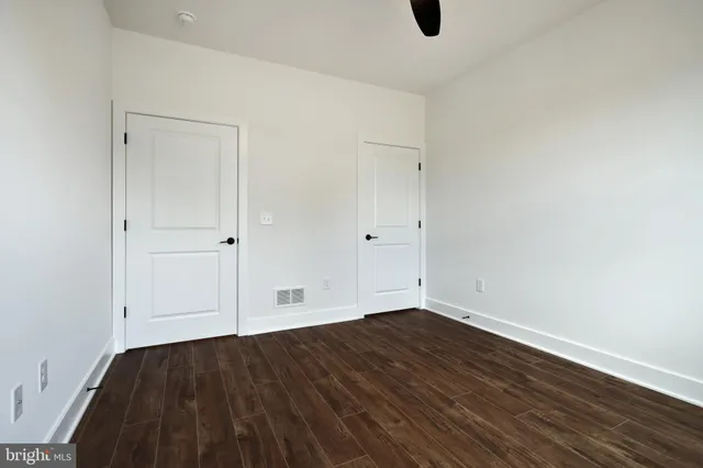 a view of an empty room with wooden floor fireplace and a window