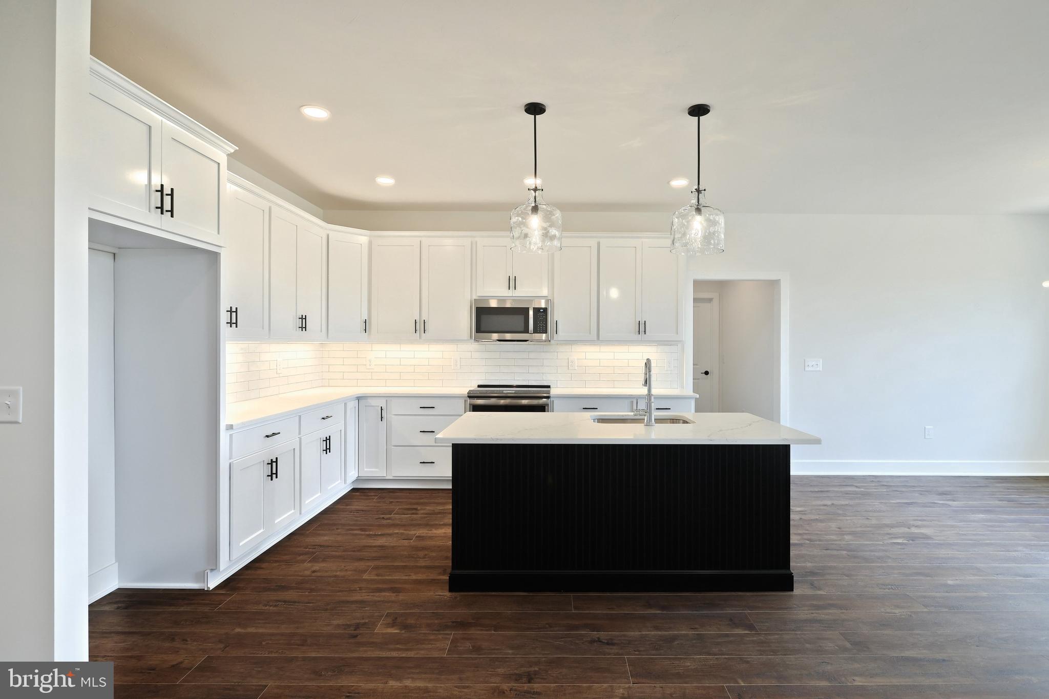 559 Lumber Street Littlestown, PA 17340 - Photo 24 of 73 a kitchen with stainless steel appliances granite countertop a sink stove a refrigerator and white cabinets with wooden floor